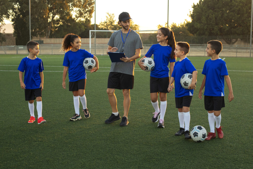 front view football trainer teaching kids field (1)